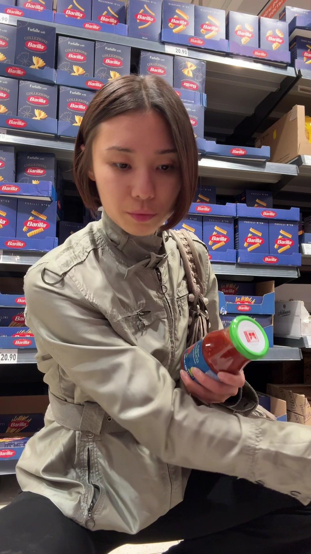 Woman Comparing Pasta Sauces in Store